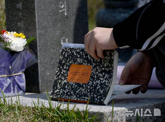[광주=뉴시스] 김혜인 기자=광주 5·18민주화운동 45주년 엿새를 앞둔 12일 오전 광주 북구 국립 5·18민주묘지에서 학생들이 한강 작가의 '소년이 온다' 책 주인공 '동호' 실존 인물인 문재학 열사의 묘소를 참배하던 중 소설 '소년이 온다'를 제단에 바치고 있다. 2025.05.12. hyein0342@newsis.com