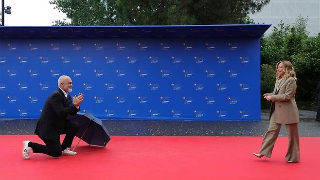 멜로니 총리를 무릎꿇고 환영하는 라마 총리. AP=연합뉴스