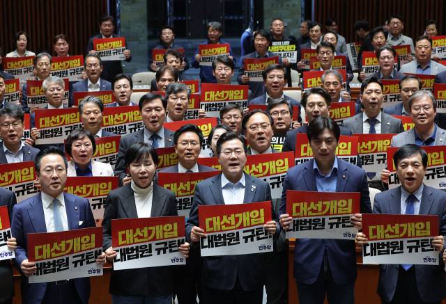 더불어민주당 박찬대 원내대표를 비롯한 의원들이 지난 4일 국회에서 열린 긴급 의원총회에서 대법원 규탄 팻말을 들고 구호를 외치고 있다. 연합뉴스