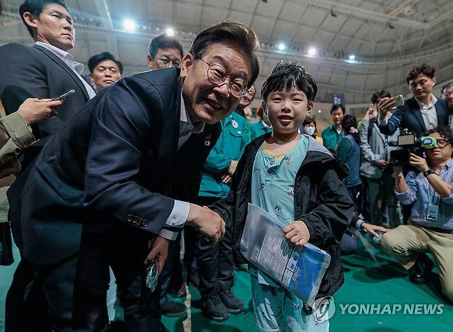 금호타이어 화재 대피소 찾은  이재명 대선후보 (광주=연합뉴스) 황광모 기자 = 더불어민주당 이재명 대선후보가 17일 광주광역시 광산구 광주여대 체육관에 마련된 금호타이어 공장 화재 이재민 대피소를 찾아 악수를 요청하는 어린이와 악수하고 있다. 2025.5.18 [공동취재] hkmpooh@yna.co.kr