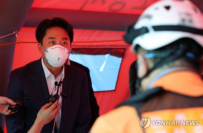 개혁신당 이준석 대선후보가 19일 오후 광주 광산구 금호타이어 광주공장 화재 현장에서 소방 관계자의 브리핑을 받고 있다. /연합뉴스