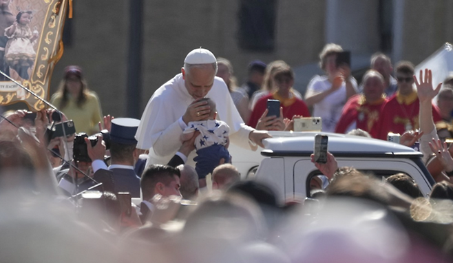 18일(현지시간) 레오 14세 교황이 성 베드로 광장에서 신자들이 들어올린 아기의 이마에 입을 맞추고 있다. ⓒAP/연합뉴스