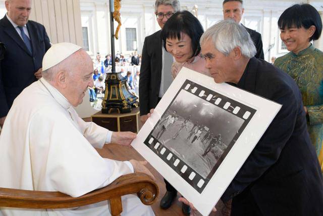 베트남전 참상이 담긴 '네이팜탄 소녀' 촬영자로 알려진 사진 기자 닉 우트(오른쪽 두 번째)와 사진 속 주인공인 판 티 킴 푹(오른쪽 세 번째)이 2022년 5월 바티칸에서 프란치스코 교황에게 사진을 전달하고 있다. 바티칸=AFP 연합뉴스 자료사진