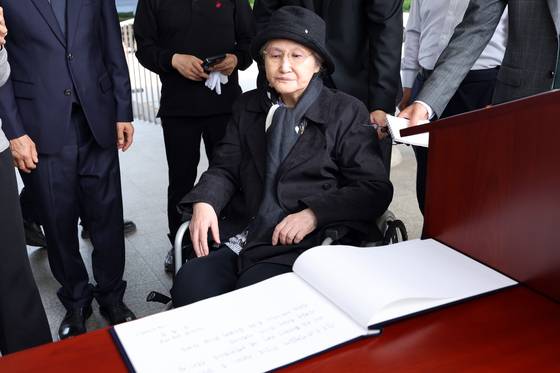 19일 노태우 전 대통령의 부인 김옥숙 여사가 광주 북구 국립5·18민주묘지에서 참배를 마치고 아들 재헌 동아시아 문화센터 원장이 대필한 방명록을 바라보고 있다. 연합뉴스