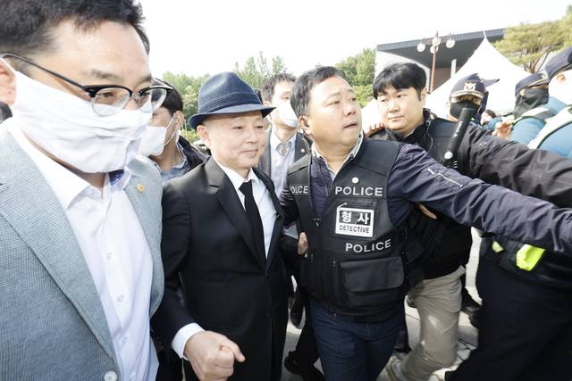 제45주년 5·18 민주화운동 기념식이 열린 18일 오전 광주 북구 운정동 국립 5·18 민주묘지 민주의문 앞에서 시민들의 항의를 받은 안창호 국가인권위원장이 경호를 받으며 돌아가고 있다.  [공동취재] 연합뉴스