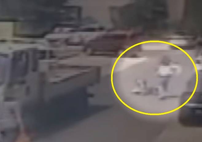 중국 산둥성 칭다오법원이 공개한 당시 사건 장면을 담은 CCTV 영상 중 일부. 앞서 걷던 류씨(원 안)가 뒤에서 휴대전화를 보며 걷던 왕씨와 충돌해 넘어져 있다. [ SCMP 갈무리]