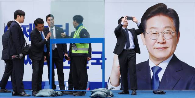 19일 서울 영등포구 타임스퀘어 광장에서 이재명 더불어민주당 대선 후보의 선거유세 시작 전 경호원들이 방탄유리를 설치하고 있다. 오승현 기자 2025.05.19