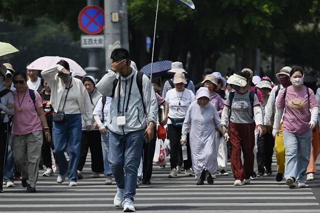 20일 중국 베이징의 한 거리에서 시민들이 길을 건너고 있다. (사진=AFP)