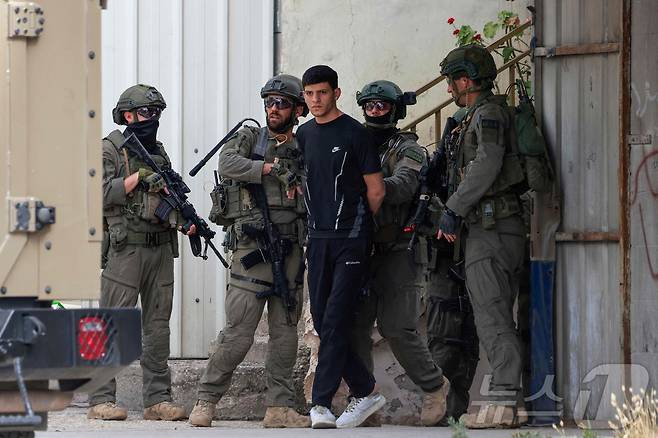 18일(현지시간) 이스라엘 군이 서안지구 나블루스시에서 팔레스타인 남성을 구금하고 있다. ⓒ AFP=뉴스1