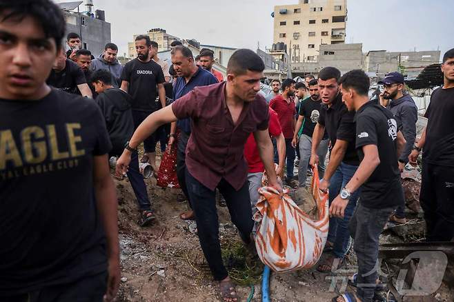 팔레스타인 시민들이 18일(현지시간) 가자지구 북부 자발리아 서쪽 알사프타위 지역 이스라엘의 공격 현장에서 희생자를 옮기고 있다. ⓒ AFP=뉴스1