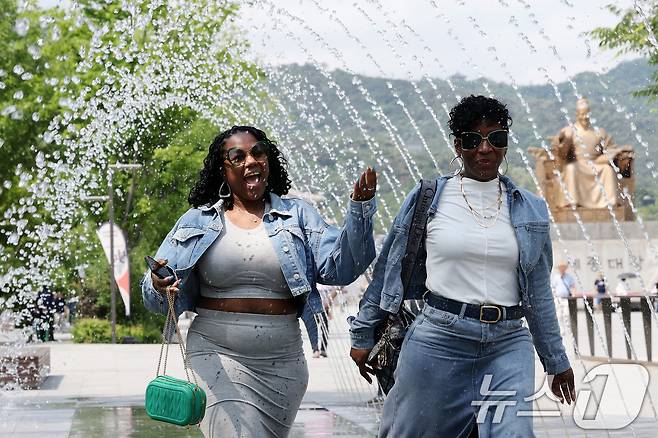 전국 대부분 지역 낮 기온이 25도 이상으로 올라 초여름 날씨를 보인 20일 서울 종로구 광화문광장 분수터널에서 외국인 관광객들이 더위를 식히고 있다. 2025.5.20/뉴스1 ⓒ News1 이동해 기자