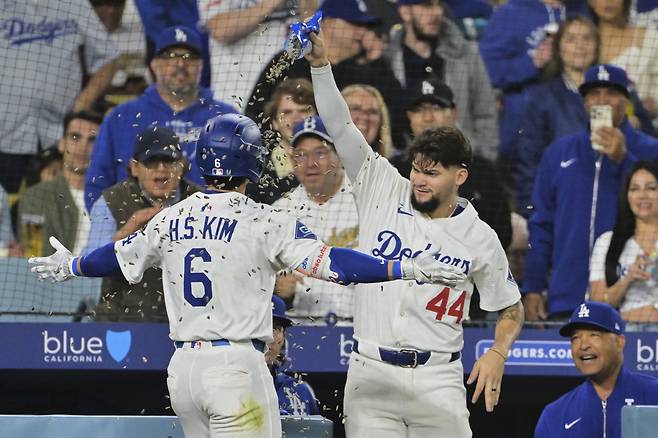 김혜성이 빅리그 첫 홈런포를 쏘아올리고 들어오자 데이브 로버츠 감독이 활짝 웃으며 해바라기씨 세례를 받는 그를 바라보고 있다. AP연합뉴스