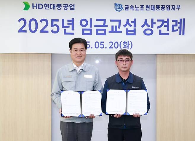 20일 HD현대중공업 울산본사에서 열린 '2025년 임금교섭 상견례'에서 이상균 HD현대중 사장(왼쪽)과 백호선 금속노조 현대중공업지부장이 임금교섭 기본사항 합의서를 들고 기념 촬영을 하고 있다. ⓒHD현대중공업