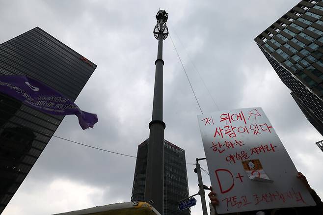 김형수 금속노조 거제통영고성조선하청지회장이 원청인 한화오션에 임금 직접 교섭을 요구하며 서울 중구 한화빌딩 앞 30m 폐회로텔레비전(CCTV) 철탑에 올라 고공농성에 돌입한 이튿날인 3월16일 오전, 조합원이 철탑 아래서 손팻말을 들고 있다. 김영원 기자 forever@hani.co.kr