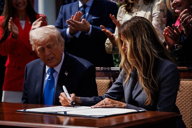 도널드 트럼프 대통령의 아내 멜라니아 트럼프가 19일 백악관 로즈 가든에서 디지털 성폭력 척결을 위한 ‘테이크 잇 다운’ 법안에 트럼프 대통령과 함께 서명하고 있다. UPI 연합뉴스