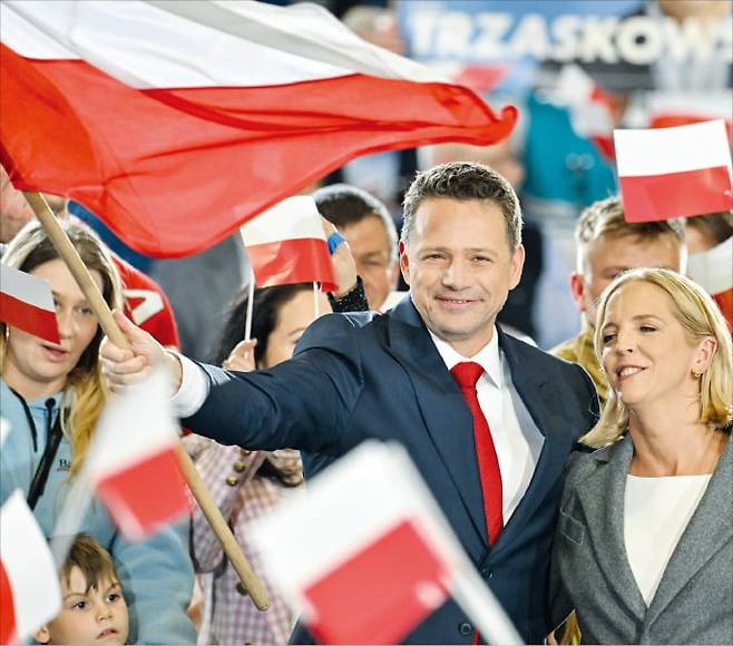 18일(현지시간) 폴란드 대선 1차투표에서 1위로 결선투표에 오를 것으로 예상되는 라파우 트샤스코프스키 후보가 부인과 함께 폴란드 국기를 흔들고 있다.   EPA연합뉴스
