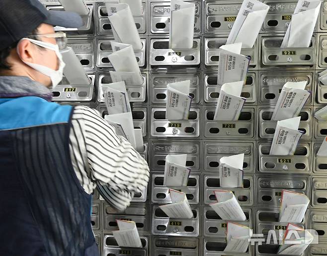 [수원=뉴시스] 김종택 기자 = 18일 경기 수원시 권선구 한 오피스텔 건물에서 우체국 집배원이 제21대 대통령선거 안내문과 선거공보물을 우편함에 넣고 있다. 2025.05.18. jtk@newsis.com