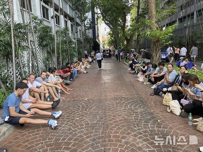 [방콕=AP/뉴시스] 3월 28일태국 방콕의 주거용 건물에서 대피한 주민들이 집으로 돌아가도 된다는 안내를 기다리며 대기하고 있다. 이날 미얀마 만달레이에서 규모 7.7의 강진이 발생해 인접국인 태국 방콕에서 건설 중이던 30층 건물이 무너져 최소 10명이 숨지고 약 100명이 매몰된 것으로 알려졌다. 2025.05.20.