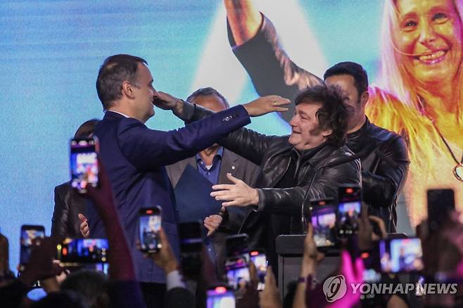 18일(현지시간) 밀레이 아르헨티나 대통령(오른쪽)으로부터 축하 받는 아도르니 대변인 [부에노스아이레스 EPA=연합뉴스. 재판매 및 DB 금지]