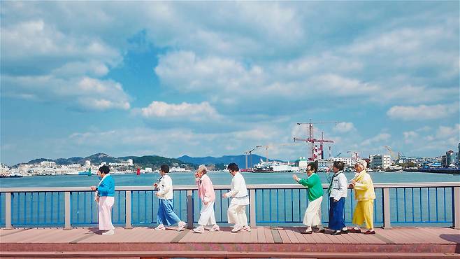 “우리는 칠곡할매래퍼!” 통영 바닷가 산책로를 랩 박자에 맞춰 행진 중인 수니와칠공주. 형형색색의 복장과 배경이 어우러져 마치 한 편의 뮤직비디오 같은 장면이 연출됐다. /칠곡군 제공