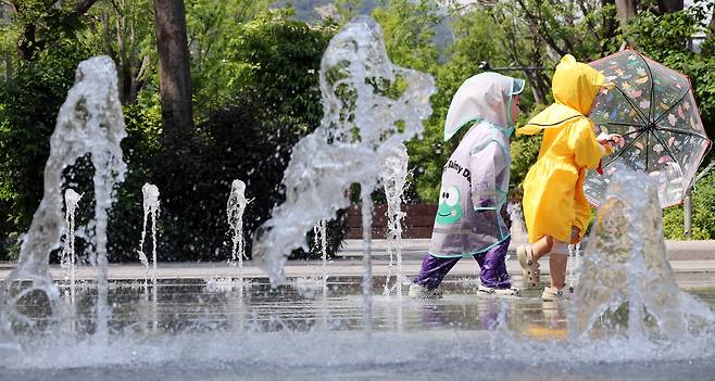 전국 대부분 지역 낮 기온이 25도 이상으로 올라 초여름 날씨를 보인 20일 서울 종로구 광화문광장 바닥분수에서 우의를 입은 어린이들이 물놀이를 하며 더위를 식히고 있다. /뉴스1
