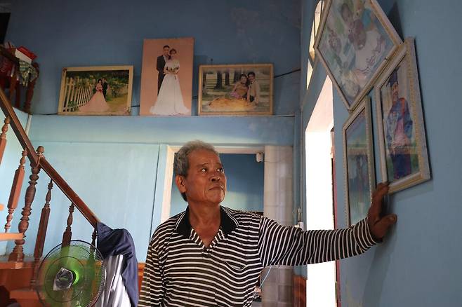 쯔엉떤트엉이 자신의 집에서 출가한 딸들의 사진을 보며 생각에 잠겨 있다.