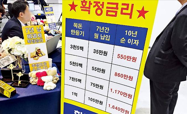 지난 18일 서울 삼성동 코엑스에서 열린 한 박람회에서 시민들이 생명보험 판매 부스를 찾아 상담받고 있다. ‘추첨을 통해 순금 제공’ ‘월 55만원을 10년간 납입했을 때 순이자 860만원’이라는 안내판이 붙어 있다.  독자 제공