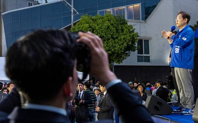 더불어민주당 이재명 대선후보가 15일 전남 목포시 평화광장 원형상가 앞에서 열린 유세에서 지지를 호소하는 연설을 하고 있다. 
    유세차 아래에서 경찰 경호 관계자가 테러 위협에 대응하기 위해 특수 쌍안경을 이용해 근처 건물을 계속 지켜보고 있다. 사진=연합뉴스