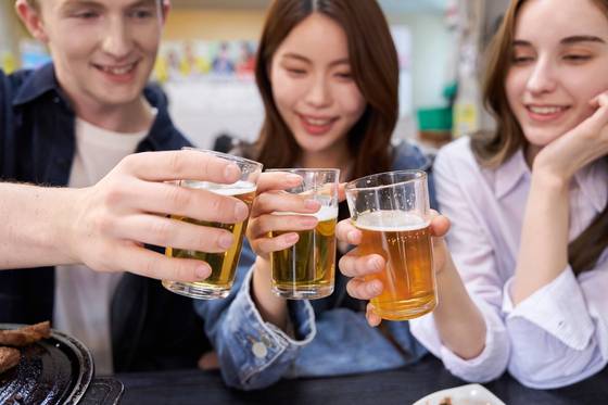 People toast with somaek, one of the most beloved drinks among Koreans and a staple at company gatherings. [GETTY IMAGES]