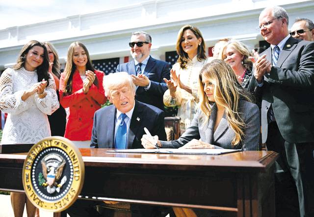 도널드 트럼프 미국 대통령이 19일(현지시간) 백악관 로즈가든에서 부인 멜라니아 여사가 ‘테이크 잇 다운’ 법안에 추가 서명하는 것을 지켜보고 있다. AFP연합뉴스