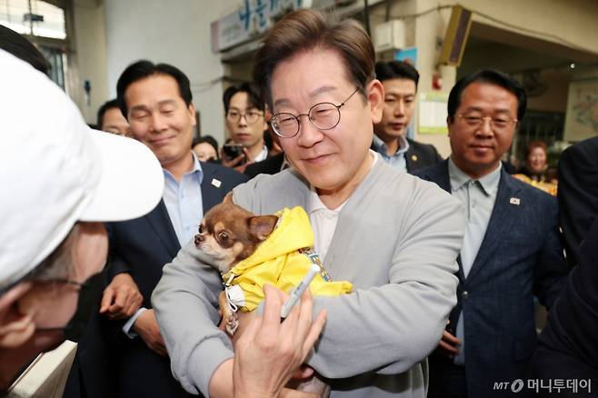 [강진=뉴시스] 조성우 기자 = 민심을 청취하는 '경청 투어'에 나선 이재명 더불어민주당 대선후보가 11일 전남 강진군 강진오감통시장에서 한 주민의 강아지를 안아보고 있다. 2025.05.11. xconfind@newsis.com /사진=조성우