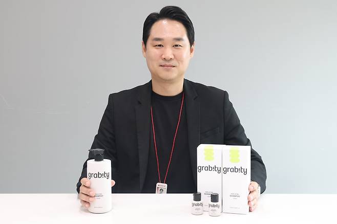 이준영 롯데홈쇼핑 뷰티팀장이 20일 헤럴드경제와 가진 인터뷰에서 그가 발굴한 그래비티 탈모샴푸 제품을 선보이고 있다. [롯데홈쇼핑 제공]