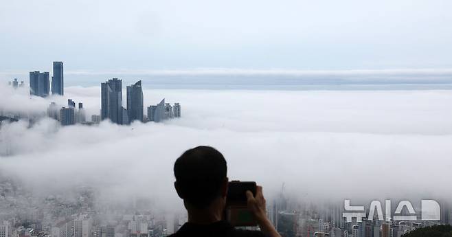 [부산=뉴시스] 하경민 기자 = 초여름 더위가 이어진 21일 부산 황령산의 한 전망대를 찾은 시민이 짙은 해무로 뒤덮인 도심을 휴대전화로 촬영하고 있다. 2025.05.21. yulnetphoto@newsis.com