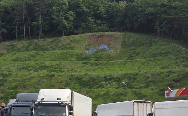 ▲ 수동휴게소를 건축하기 위해 절개한 법면이 붕괴해 임시방편으로 덮개를 설치했지만 잦은 토사 유출로 통행 차량의 안전을 방해하고 있다.