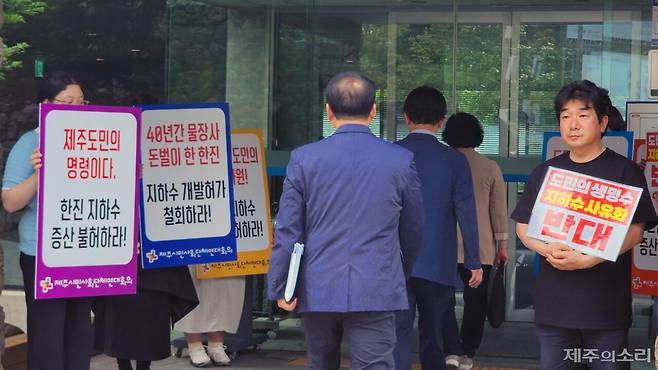 제주특별자치도 통합물관리위원회 지하수관리분과위원회가 열린 제주문학관으로 들어가고 있는 위원들과 지하수 증산 반대 피켓 시위를 벌이고 있는 제주시민사회단체연대회의. ⓒ제주의소리