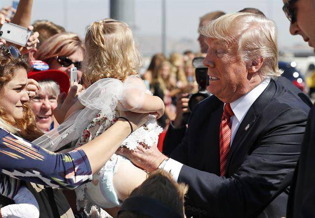 도널드 트럼프 미국 대통령이 2018년 8월 23일 미 네바다주 레노에서 아기를 안으려 힘겨운 표정을 짓고 있다. AP 연합뉴스