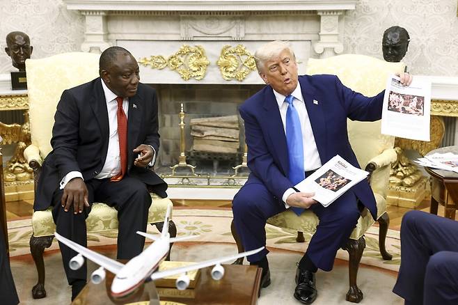 도널드 트럼프 미국 대통령(오른쪽)이 21일(현지시간) 미국 워싱턴DC 백악관 집무실에서 시릴 라마포사 남아프리카공화국 대통령과 정상회담을 하던 중 남아공의 '백인 농부 집단살해' 의혹이 담긴 문서를 들어 보이고 있다.  EPA연합뉴스