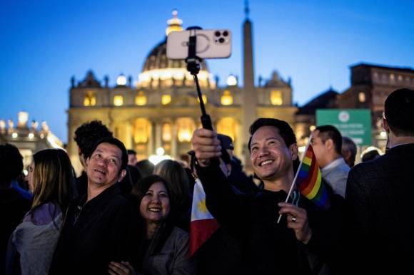 이탈리아 로마에서 성 베드로 대성당이 배경으로 보이는 가운데 필리핀 출신의 한 남성이 성소수자 깃발을 들고 포즈를 취하고 있다. 2025.4.25 로이터 연합뉴스