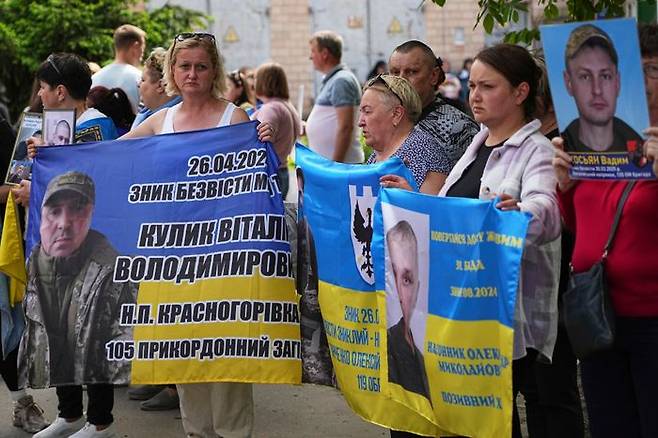 23일(현지 시간) 우크라이나 체르니히우에서 러시아와 우크라이나 간 포로 교환을 앞두고 우크라이나 포로 가족들이 억류 중인 병사들의 사진과 플래카드를 들고 있다.ⓒ체르니히우=AP/뉴시스