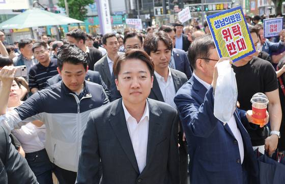 개혁신당 이준석 대선 후보가 21일 경기 성남의료원에 도착, 시민단체 회원들의 항의를 받으며 들어서고 있다. 연합뉴스