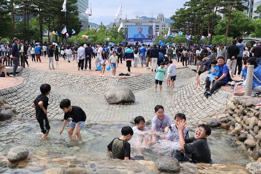 24일 더불어민주당 이재명 대선 후보가 경기 안양시 동안구 평촌중앙공원에서 유세하는 가운데 유세장 인근에서 어린이들이 물놀이를 하고 있다. 뉴시스