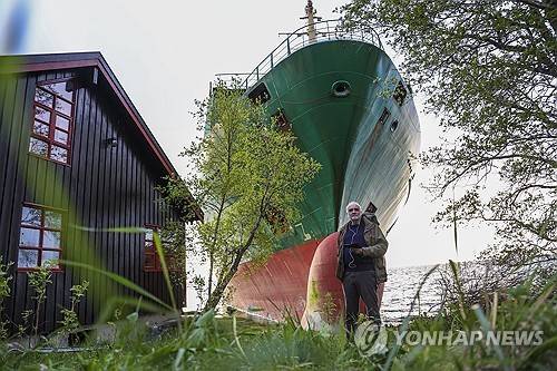 컨테이너선이 덮친 자택 앞마당에 서 있는 노르웨이 주민 (트론헤임 AP=연합뉴스) 2025년 5월 22일(현지시간) 노르웨이 트론헤임에 있는 요한 헬베르그(사진 가운데 하단) 씨의 주택 앞마당에 길이가 135ｍ인 컨테이너선 'NCL 살텐'(사진 배경)이 좌초했다. (Jan Langhaug/NTB Scanpix via AP) 2025.5.24.