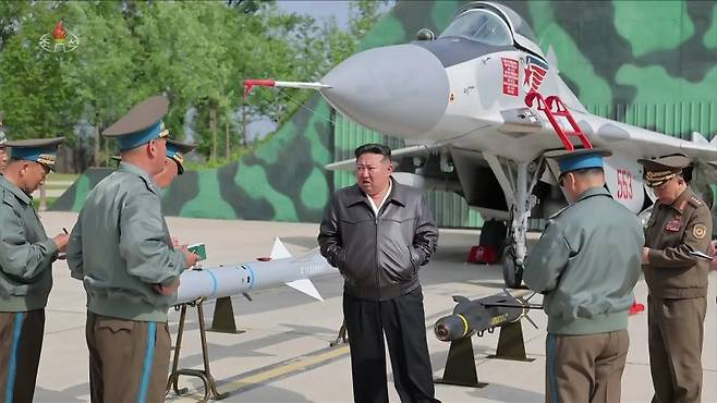 김정은 북한 국무위원장이 지난 15일 제1공군사단 관하 비행연대를 시찰하면서 공개한 첨단능동레이더공대공미사일(AAM)이 김정은 오른팔 옆에 설치돼 있다. 그러나 뒷면의 미그-29 오른쪽 날개 아래에 장착된 이 미사일 모습은 포토샵으로 엉성하게 붙인 것으로 보인다. 조선중앙TV 캡처