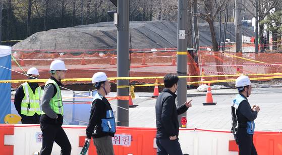 싱크홀 사고가 발생한 서울 강동구 명일동 대명초등학교 인근 사거리에서 서울 아리수 본부 관계자들이 사고 현장으로 출입하고 있다. [뉴스1]