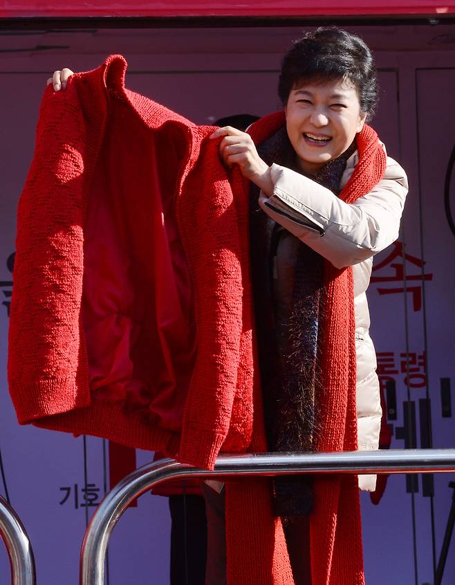 During a presidential campaign rally in Ansan, Gyeonggi Province, in December 2012, the Saenuri Party's then-candidate Park Geun-hye holds up a red jacket gifted to her by a supporter. (Herald DB)