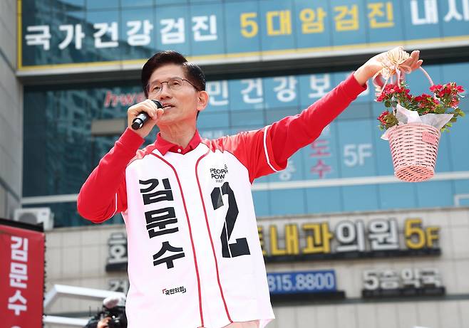 Kim Moon-soo of the People Power Party holds up a flower basket received from a supporter during a campaign rally in front of Hwajeong Station Plaza in Goyang, Gyeonggi Province, on Wednesday. (Yonhap)