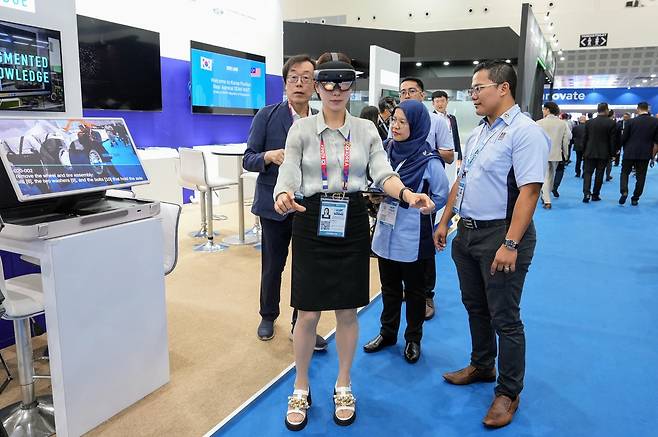 Jo Geun-sik (far left), CEO and founder of Augmented Knowledge, guides visitors through a digital twin aircraft maintenance simulator at the Korea Pavilion during LIMA 2025 in Langkawi, Malaysia, Wednesday. (Korea Defense Industry Association)