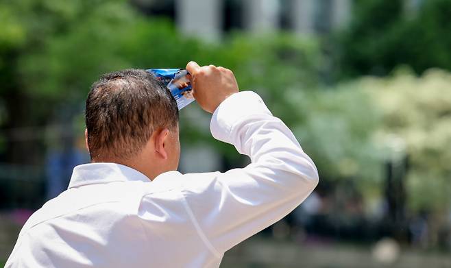 서울 중구 청계천을 찾은 한 시민이 햇빛을 가린 채 이동하고 있다./사진=뉴스1