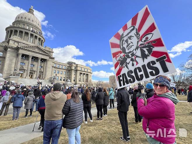 [보이시=AP/뉴시스] 미 아이다호주 보이시 의사당 앞에서 2월 5일 도널드 트럼프 대통령에 반대하는 집회에 참여한 한 여성이 트럼프 대통령을 파시스트로 묘사한 손팻말을 들고 있다. 트럼프 대통령의 강력한 이민 단속과 추방 정책에 항의하는 시위가 미국 곳곳으로 확산하는 가운데 연방법원이 멕시코로 추방된 과테말라 불법 이민을 미국으로 다시 데려오라고 트럼프 정부에게 명령했다. 2025.05.25.