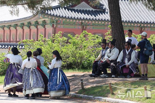 [서울=뉴시스] 김명원 기자 = 18일 서울 종로구 경복궁에서 갓과 한복을 입은 관광객들이 햇빛을 피해 휴식을 취히고 있다. 2025.05.18. kmx1105@newsis.com